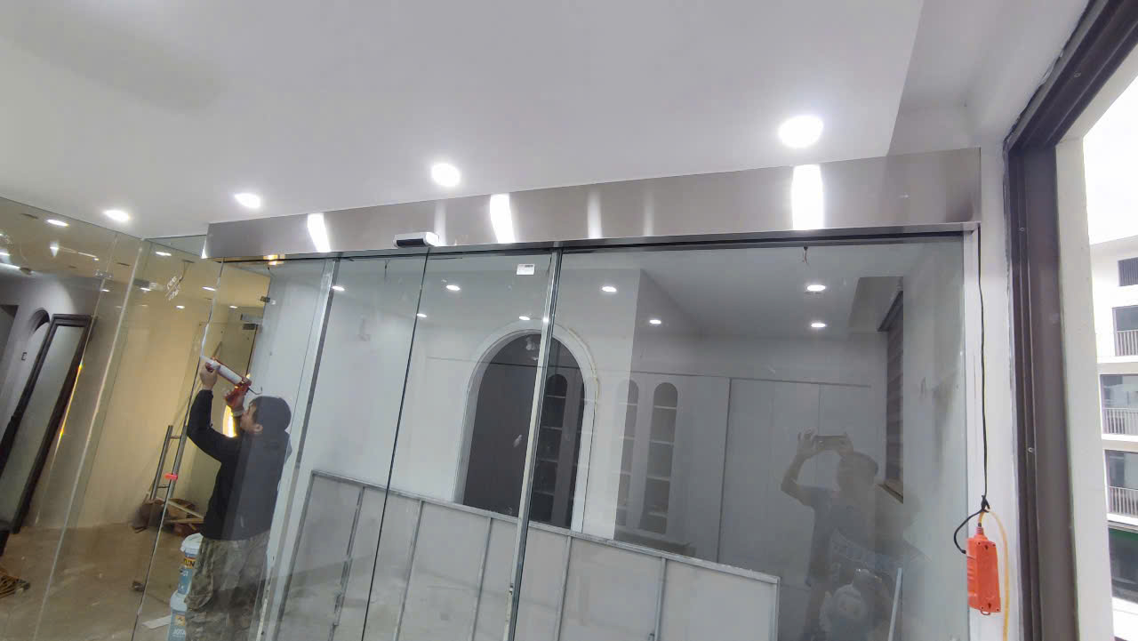 Cửa kính cường lực trượt tự động khung inox đang được thi công lắp đặt trong nhà